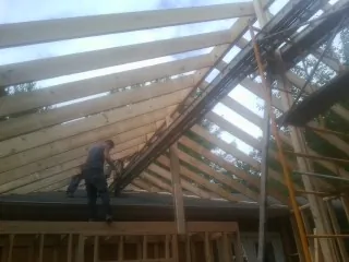 Rafters going up over a new addition with a worker on the wall in Overton