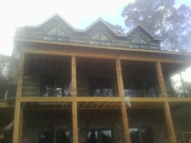 Dormers and porch framing on a large log home under construction — Roof Coating work by our crew in Overton