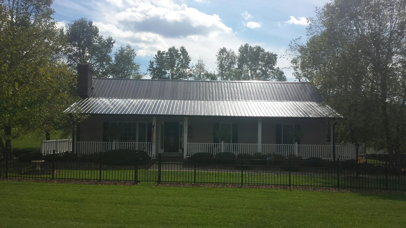 Gray metal roof on a brick ranch with a full width front porch — Gutter Guard Installation work by our crew in Overton